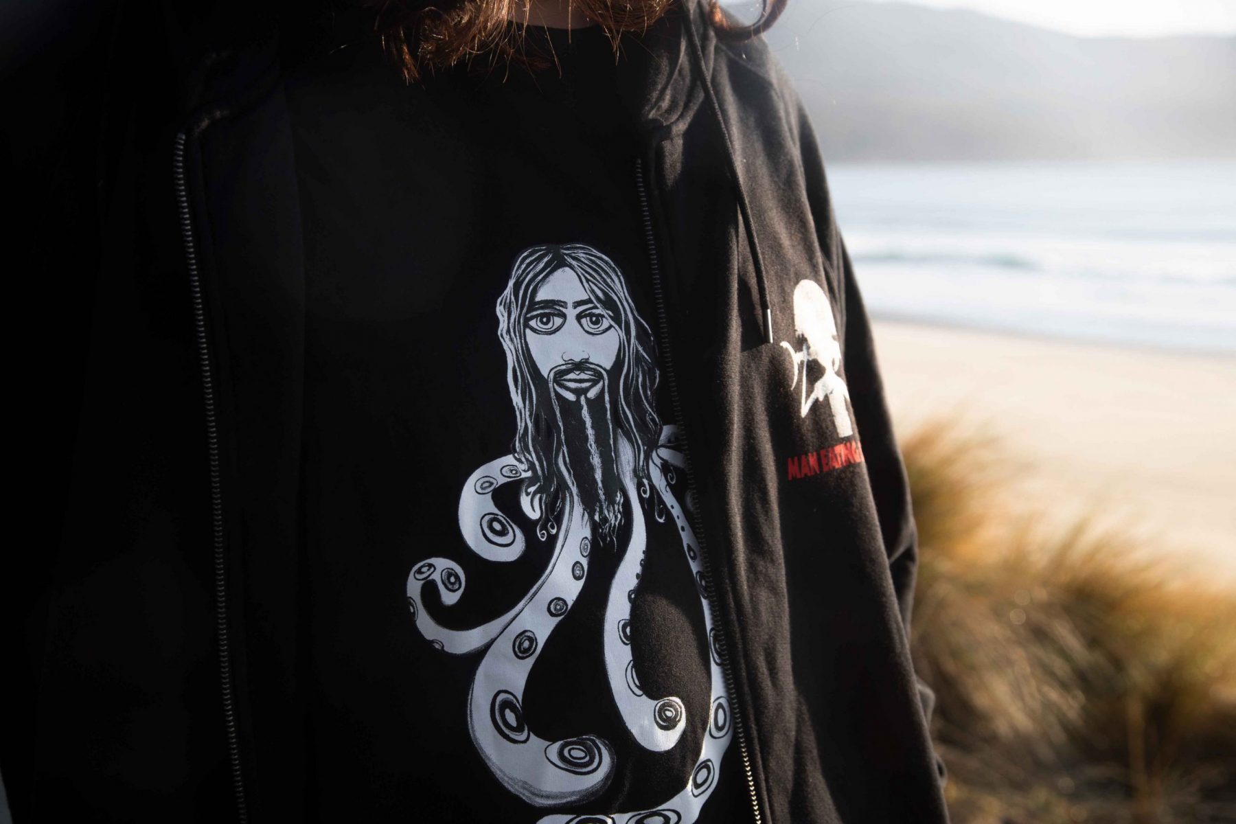 Man wearing black Hipsterpus t-shirt with beach in the background Tasmania